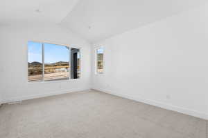 Carpeted empty room featuring a mountain view and vaulted ceiling