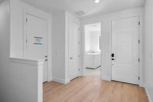 Hallway with separate washer and dryer and light hardwood / wood-style flooring