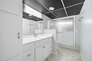 Bathroom with vanity, a shower with shower door, and toilet