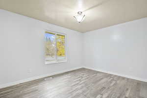 Spare room with light wood-type flooring and a textured ceiling