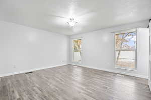 Spare room featuring a textured ceiling, light hardwood / wood-style floors, and a healthy amount of sunlight