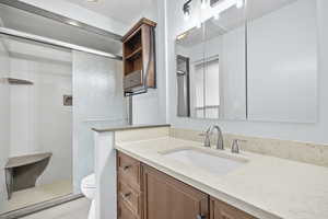 Bathroom with vanity, toilet, and an enclosed shower