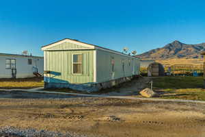 View of side of property with a mountain view and a shed