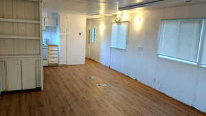 Unfurnished room featuring a textured ceiling, light wood-type flooring, and wooden walls