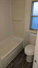 Bathroom featuring a tub to relax in, wood-type flooring, and toilet