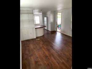 Kitchen with white cabinets, white fridge, and dark wood-type flooring