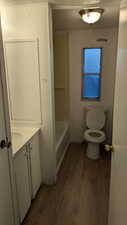 Bathroom featuring wood-type flooring, a textured ceiling, and toilet