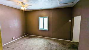 Carpeted empty room featuring ceiling fan and a textured ceiling