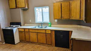 Kitchen with sink, light wood-type flooring, and white electric stove