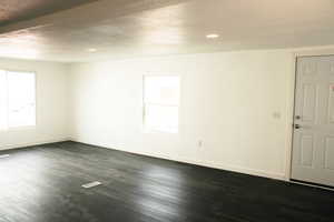 Spare room featuring a textured ceiling, a healthy amount of sunlight, and dark wood-type flooring