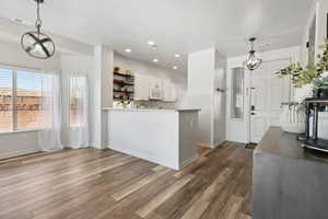 Kitchen with hardwood / wood-style floors, white cabinetry, pendant lighting, and kitchen peninsula