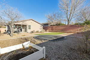 View of yard featuring a trampoline and a patio