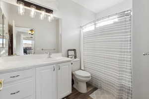 Bathroom with toilet, vanity, a shower with curtain, and hardwood / wood-style floors