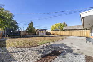 View of yard featuring a patio area, a storage unit, and a trampoline