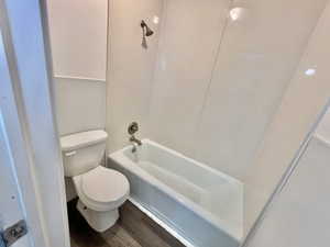 Bathroom featuring wood-type flooring, toilet, and shower / tub combination