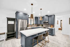 Kitchen featuring a center island, sink, hanging light fixtures, light hardwood / wood-style flooring, and stainless steel appliances