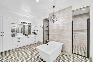 Bathroom featuring vanity, a chandelier, and shower with separate bathtub