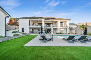 Rear view of house featuring a yard, ceiling fan, a balcony, and a patio