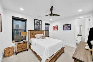 Bedroom with ensuite bath, ceiling fan, and light colored carpet