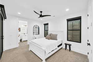 Bedroom with light carpet, ensuite bath, and ceiling fan