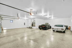 Garage featuring secured water heater, electric panel, and a garage door opener