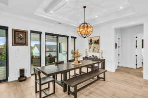 Dining area with a raised ceiling, wood ceiling, a chandelier, and light wood-type flooring