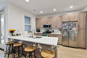 Kitchen with kitchen peninsula, appliances with stainless steel finishes, a wealth of natural light, sink, and light hardwood / wood-style flooring