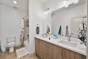 Full bathroom with toilet, vanity, shower / bath combo, and hardwood / wood-style flooring