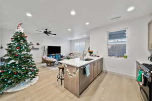 Kitchen featuring a kitchen breakfast bar, sink, light wood-type flooring, kitchen peninsula, and stainless steel appliances