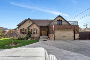 View of front of house featuring a garage, a balcony, and a front yard