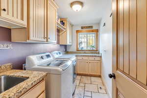 Laundry room featuring cabinets, separate washer and dryer, and sink