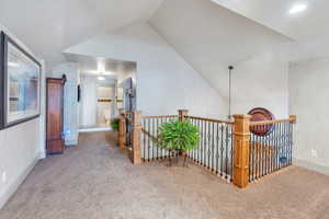 Hallway with carpet and vaulted ceiling