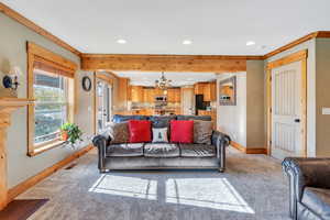 Carpeted living room with a chandelier and crown molding