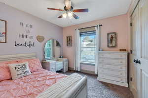 Bedroom with ceiling fan, carpet floors, and multiple windows