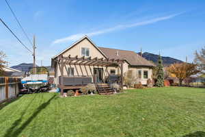 Back of house featuring a deck with mountain view, a yard, and a pergola