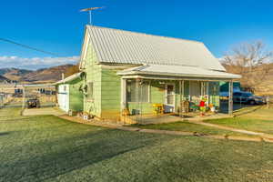 View of front of home with a mountain view, a patio, and a front lawn