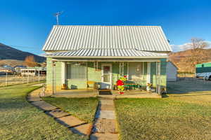 View of front facade with a mountain view, a porch, and a front yard