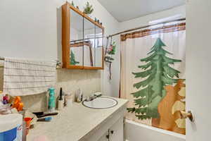 Bathroom featuring backsplash, vanity, and shower / bath combination with curtain