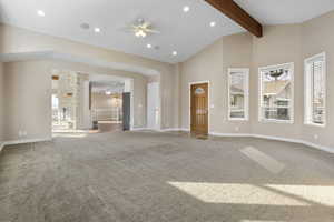 Unfurnished living room featuring beam ceiling, carpet floors, high vaulted ceiling, and ceiling fan