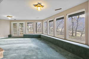 Unfurnished sunroom featuring a wealth of natural light and french doors