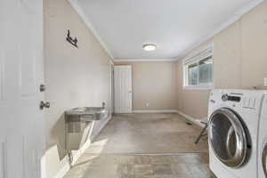 Washroom featuring washer / clothes dryer, crown molding, and light colored carpet