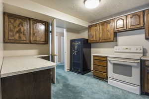 Kitchen featuring light carpet, a textured ceiling, and white electric stove