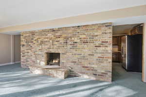 downstaires family room with dark colored carpet and a brick fireplace