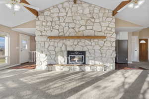 Unfurnished living room with vaulted ceiling with beams, ceiling fan, a fireplace, and dark wood-type flooring