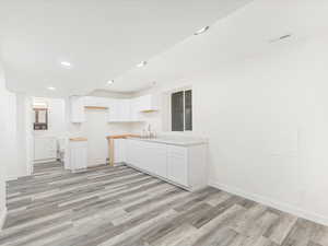 Kitchen featuring white cabinetry, sink, and  wood-style floors