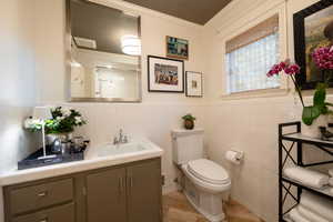 Bathroom with a shower, crown molding, toilet, vanity, and tile walls