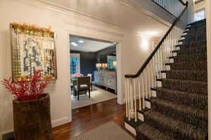 Stairway featuring hardwood / wood-style floors and crown molding