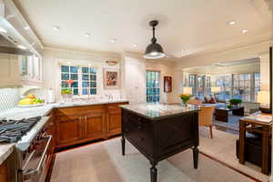 Kitchen with light stone countertops, crown molding, exhaust hood, and high end stainless steel range oven