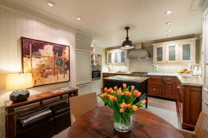 Kitchen featuring a center island, crown molding, sink, wall chimney exhaust hood, and appliances with stainless steel finishes