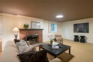 Carpeted living room with crown molding and a brick fireplace